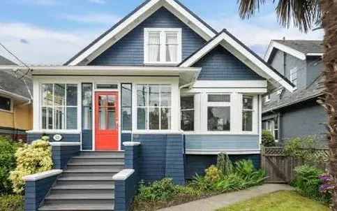 A blue character home with a steep gable, dormer and an enclosed front porch