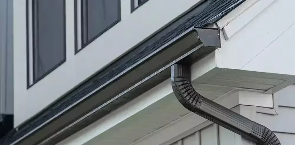 A gutter run along the eave with the downspout carrying water down the wall