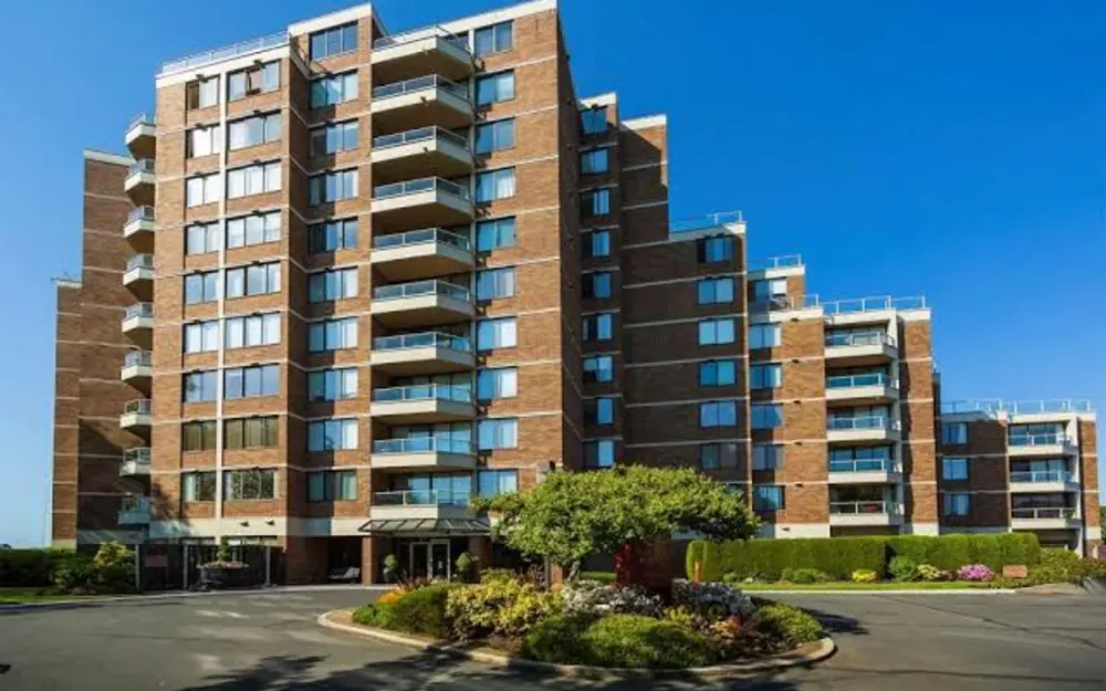 A brick strata tower with rows of balconies above a circular entry drive