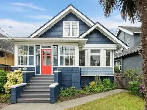 A blue character home with a steep gable, dormer and an enclosed front porch